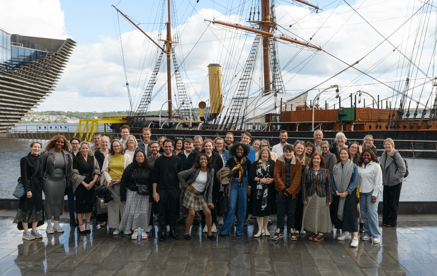 A photo of a group of people standing in front of the RRS Discovery in Dundee.